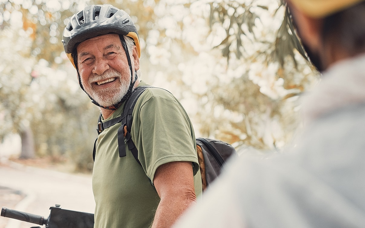 Smiling older man wearing a bicycle helmet.