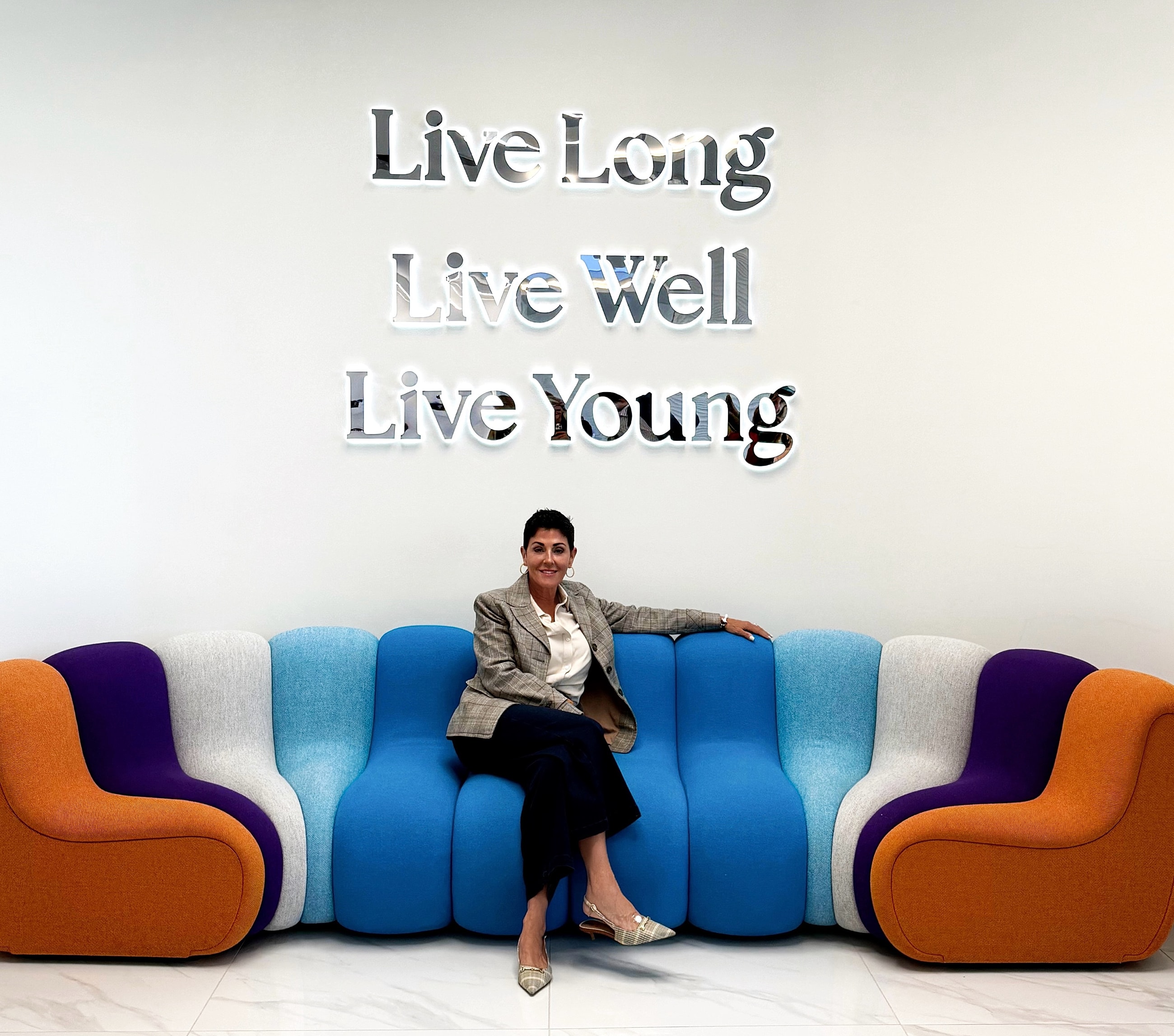 Woman smiling near textured wall and greenery