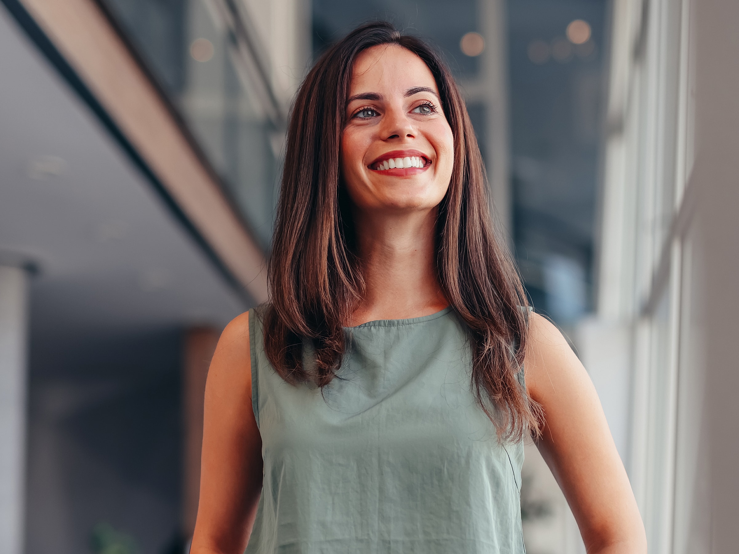 Smiling woman in green top, indoor setting.